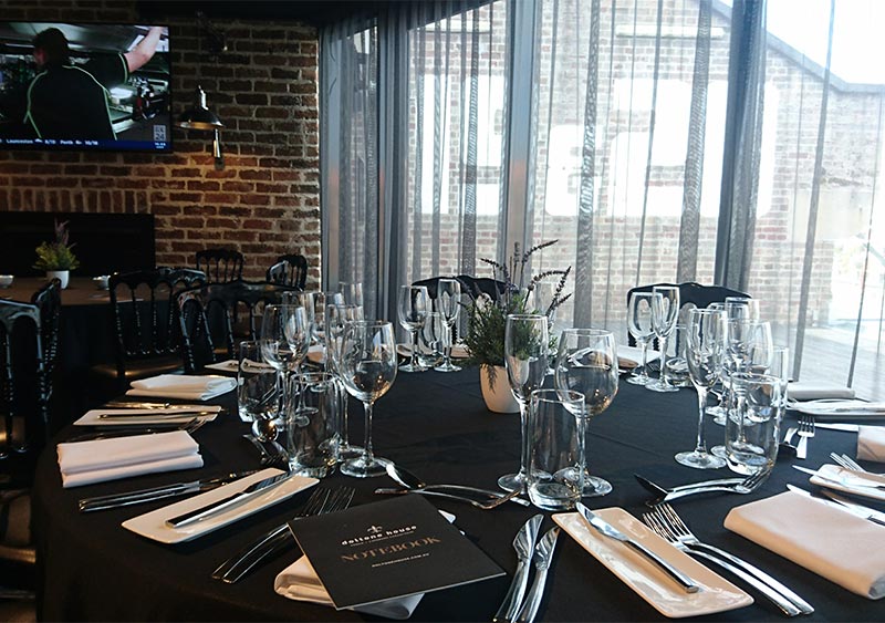 A circle table with wine glasses, knife and fork in a room covered with a black translucent curtain
