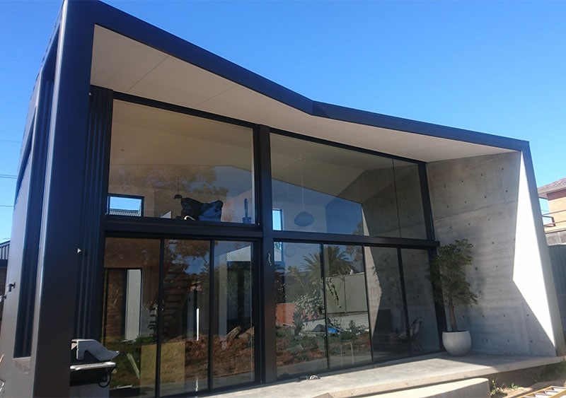 Attached to a glass house is a gray awning with a beautiful sky.